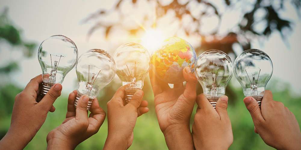 renewable energy jobs - hands holding up lightbulbs and a globe to the sun