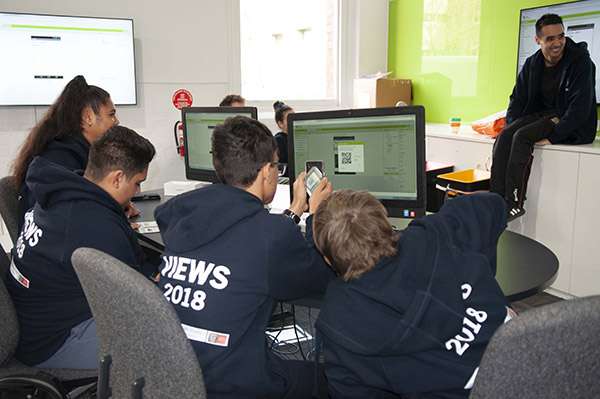 Kids wearing VIEWS jumpers at computer screens working on apps