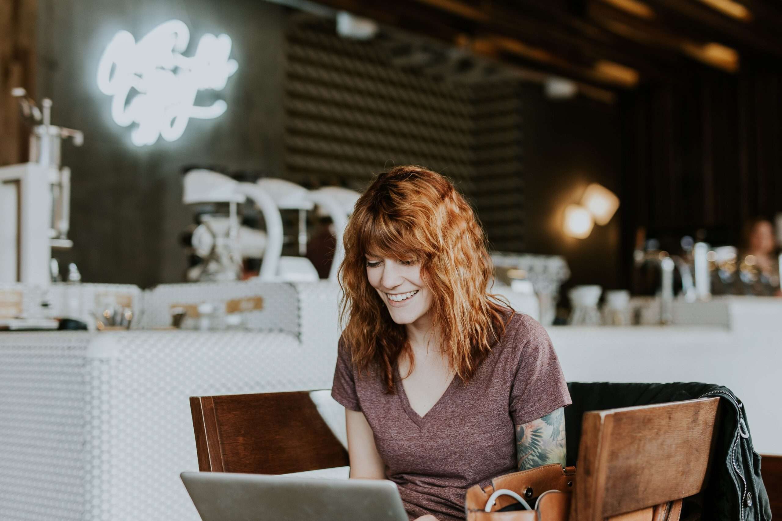 A women using a laptop in a cafe, looking happy
