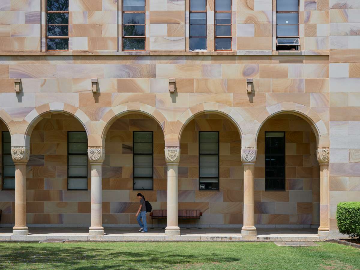 University student walking between arches on campus.