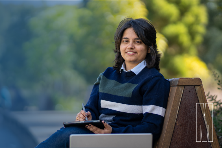 Woman with collared shirt sitting on park bench with tablet technology.