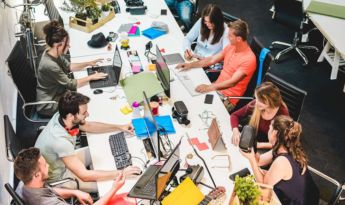 Young people in a university coworking space with laptops and monitors, uni open day