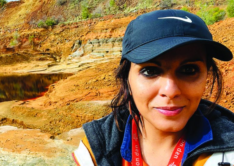 Woman wearing black cap in front of red landscape