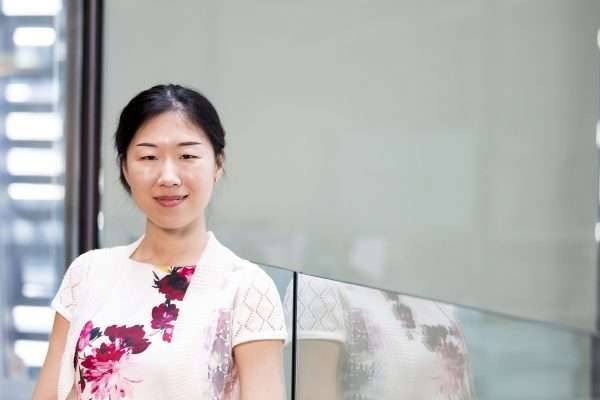 Asian woman in front of window wearing white with fuchsia orchids