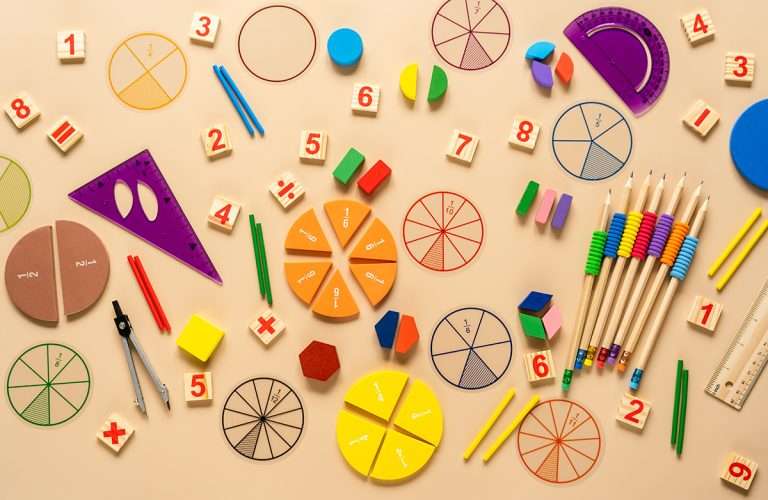 Wooden toy blocks. School supplies, math fractions, pencils, numbers, on beige background. Back to school, education concept background.