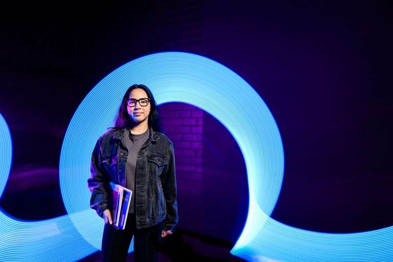 Woman holding laptop in front of blue loop background