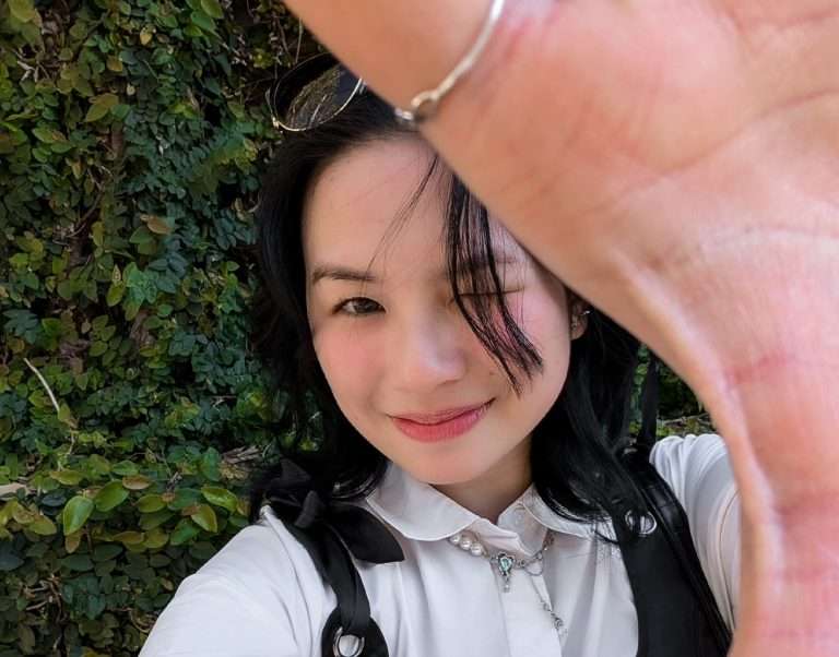 Woman looking at camera, hand partially obscuring face