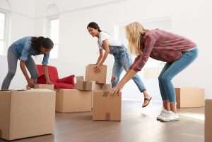 Three Female Friends Carrying Boxes Into New Home On Moving Day