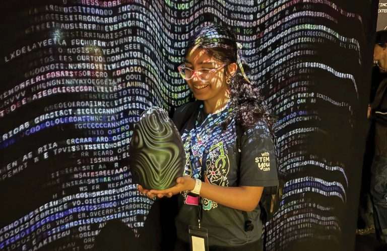 Girl holding 3D print in front of code wall