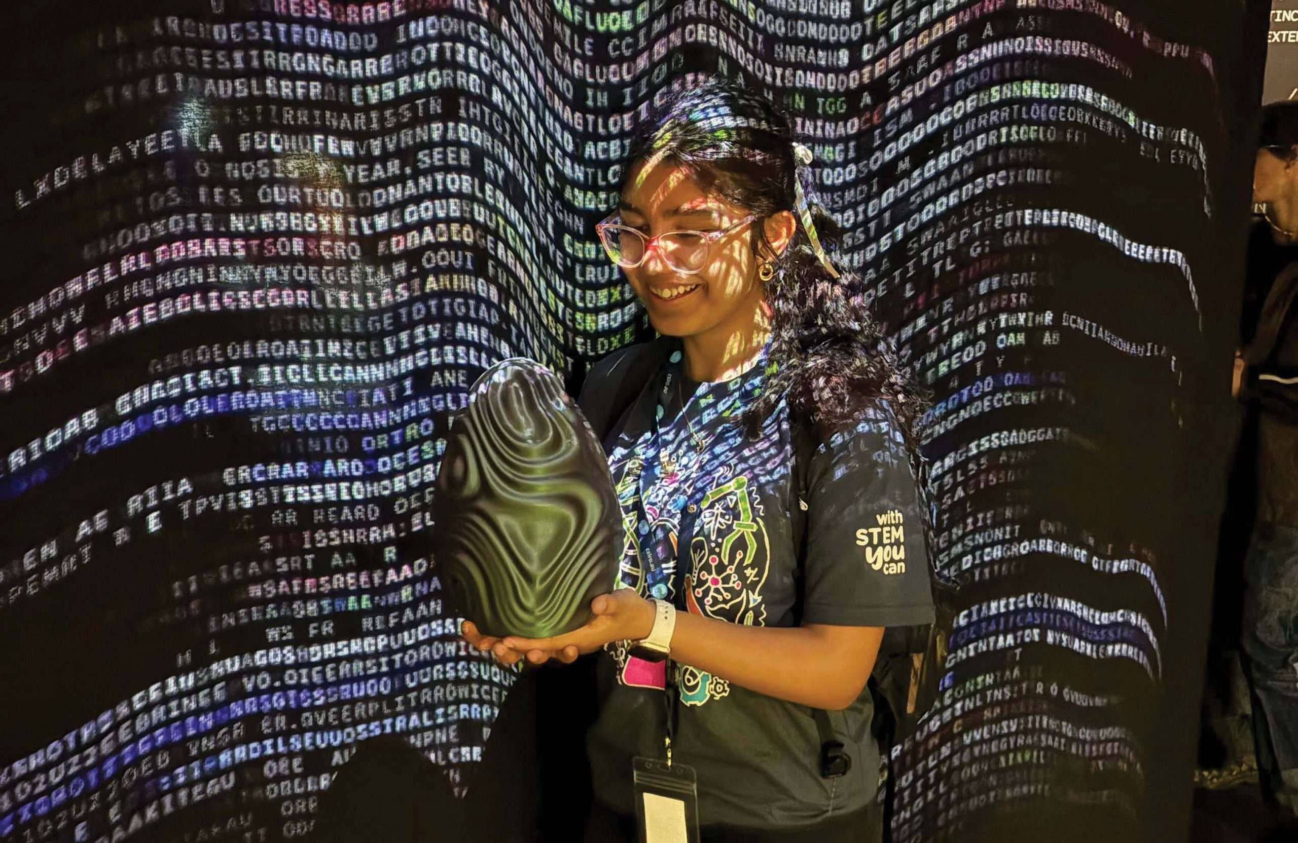 Girl holding 3D print in front of code wall