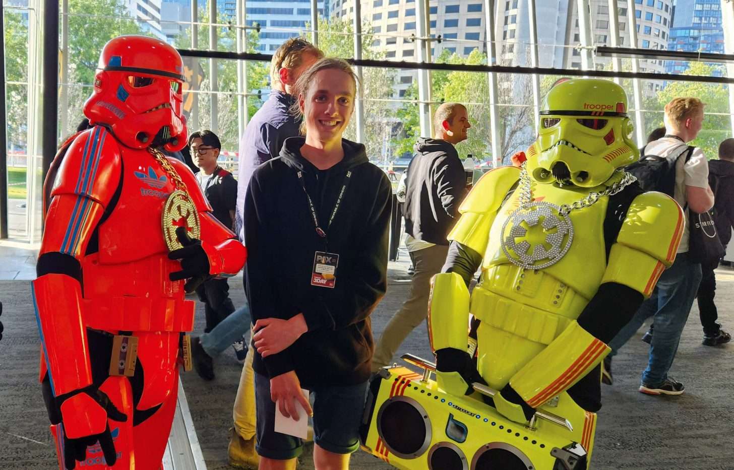 Person standing between a red stormtrooper and a yellow stormtrooper