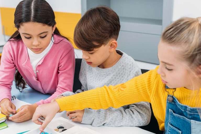 Schoolchildren sitting at desk and holding details in stem education class