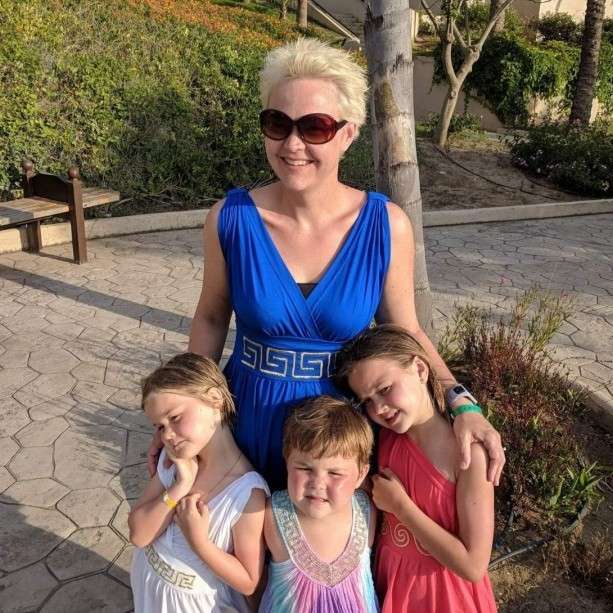 Woman in blue dress with three kids