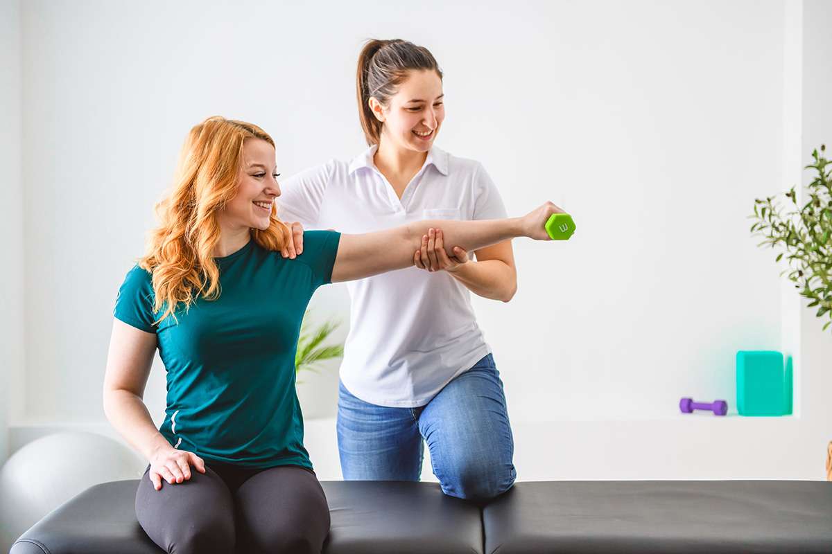 A Modern rehabilitation physiotherapy at work with client holding dumbbell