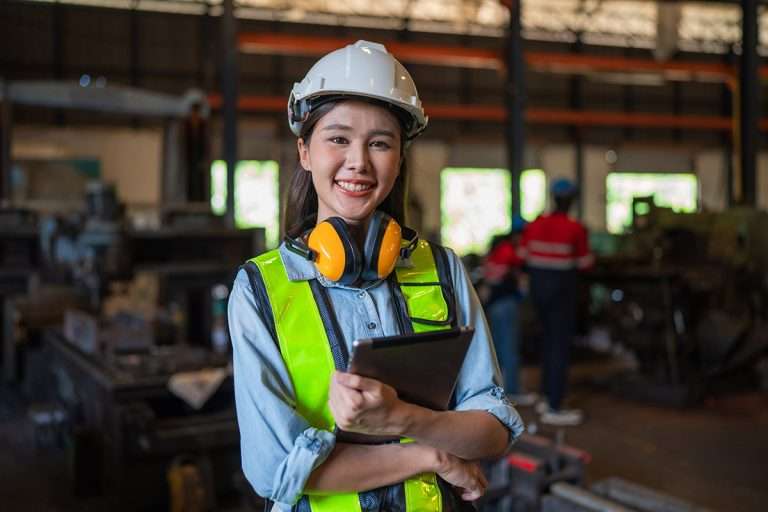 Portrait of female standing and using tablet in modern industrial factory, Woman looking camera in industrial factory.
