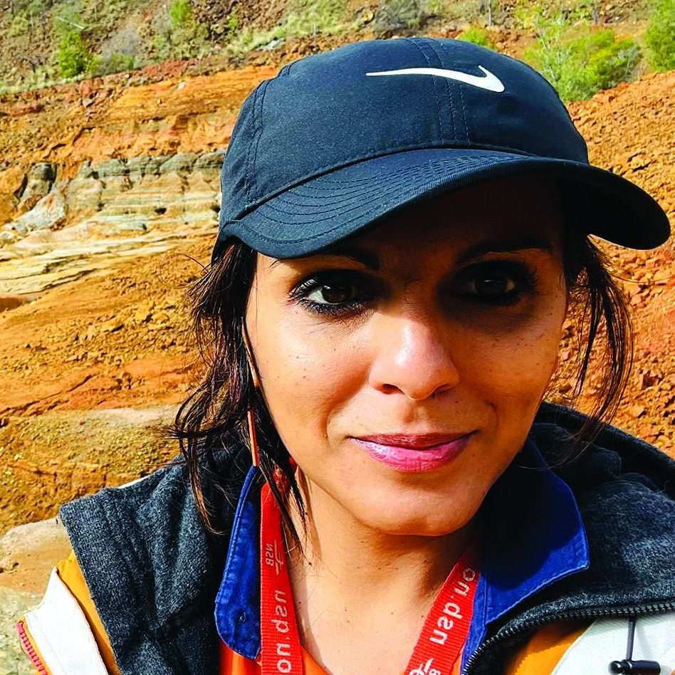 Woman wearing black cap in front of red landscape