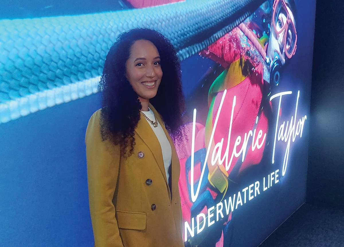 Woman with long brown curly hair and yellow jacket