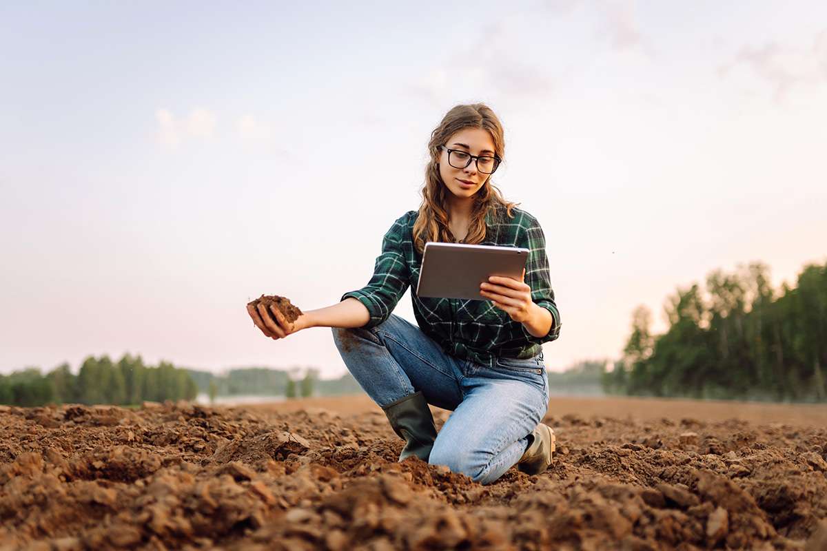 Woman checking soil, holding iPad